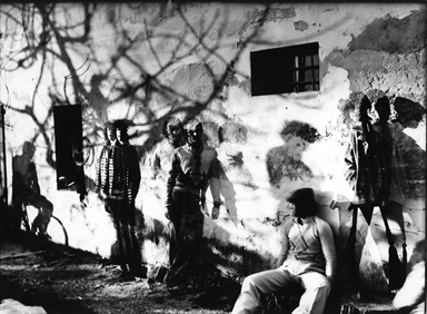 gente appoggiata al muro di una casa abbandonata tra le ombre