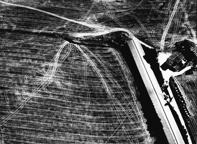 capannone e segni del trattore sui campi mietuti