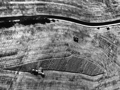 la strada e i trattori tra i campi mietuti