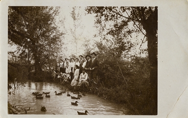 Tita Valori al centro del gruppo di giovani uomini e giovani donne che posano ai bordi di un ruscello/laghetto in cui è visibile un nutrito numero di germani reali 