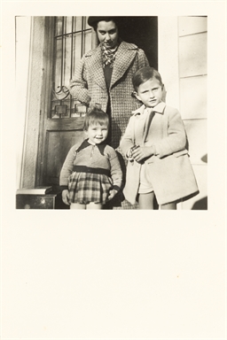 Foto di gruppo: un signora adulta con due bambini sull'uscio di una casa