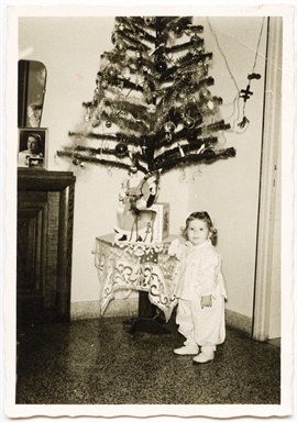 Bambina ritratta vicino ad albero natalizio