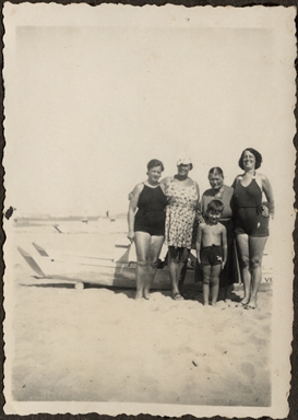 Quattro donne e un bambino ritratti sulla spiaggia con alle spalle una barca