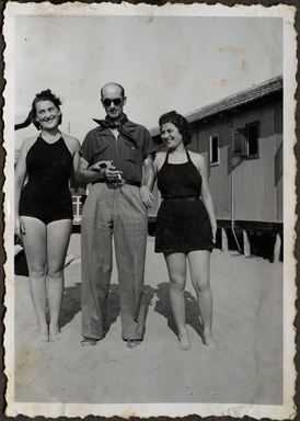 Ritratto di due ragazze e un uomo in piedi sulla spiaggia di uno stabilimento balneare