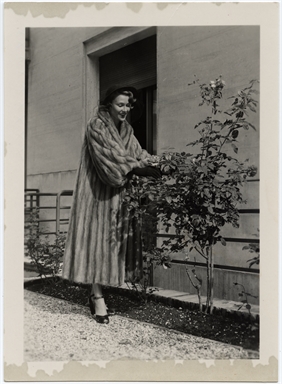 Ritratto di Vivi Gioi, in pelliccia, mentre tocca una pianta